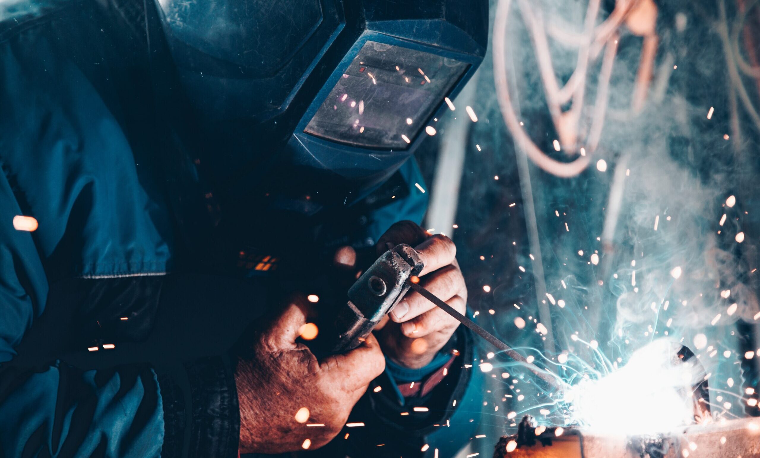 Close up of a man wearing PPE and working on a welding project.